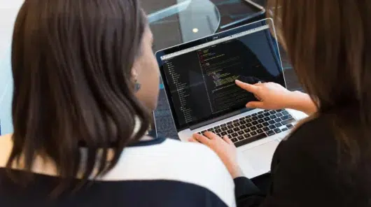 Software developers reviewing code on a laptop during a collaborative debugging session