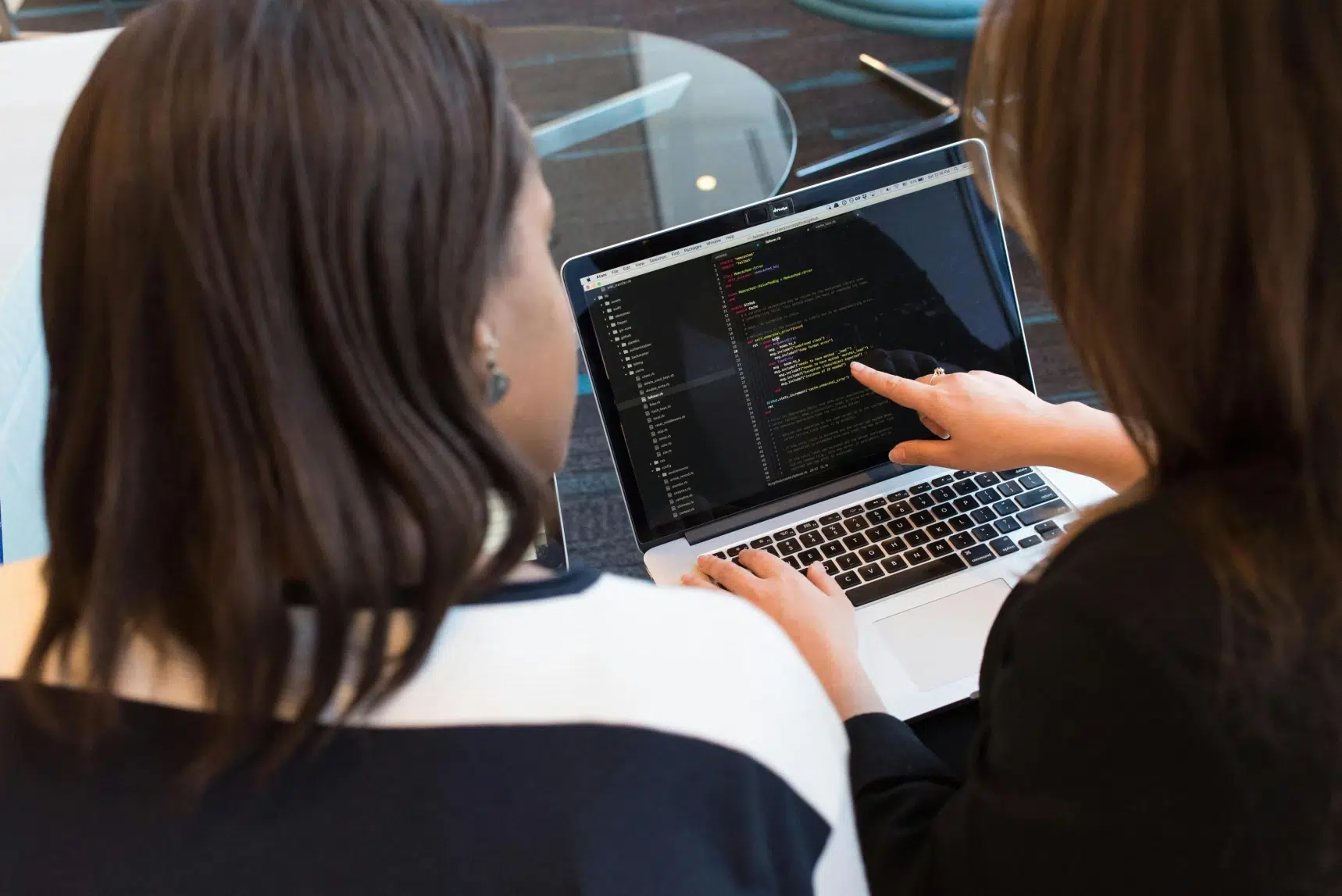 Software developers reviewing code on a laptop during a collaborative debugging session