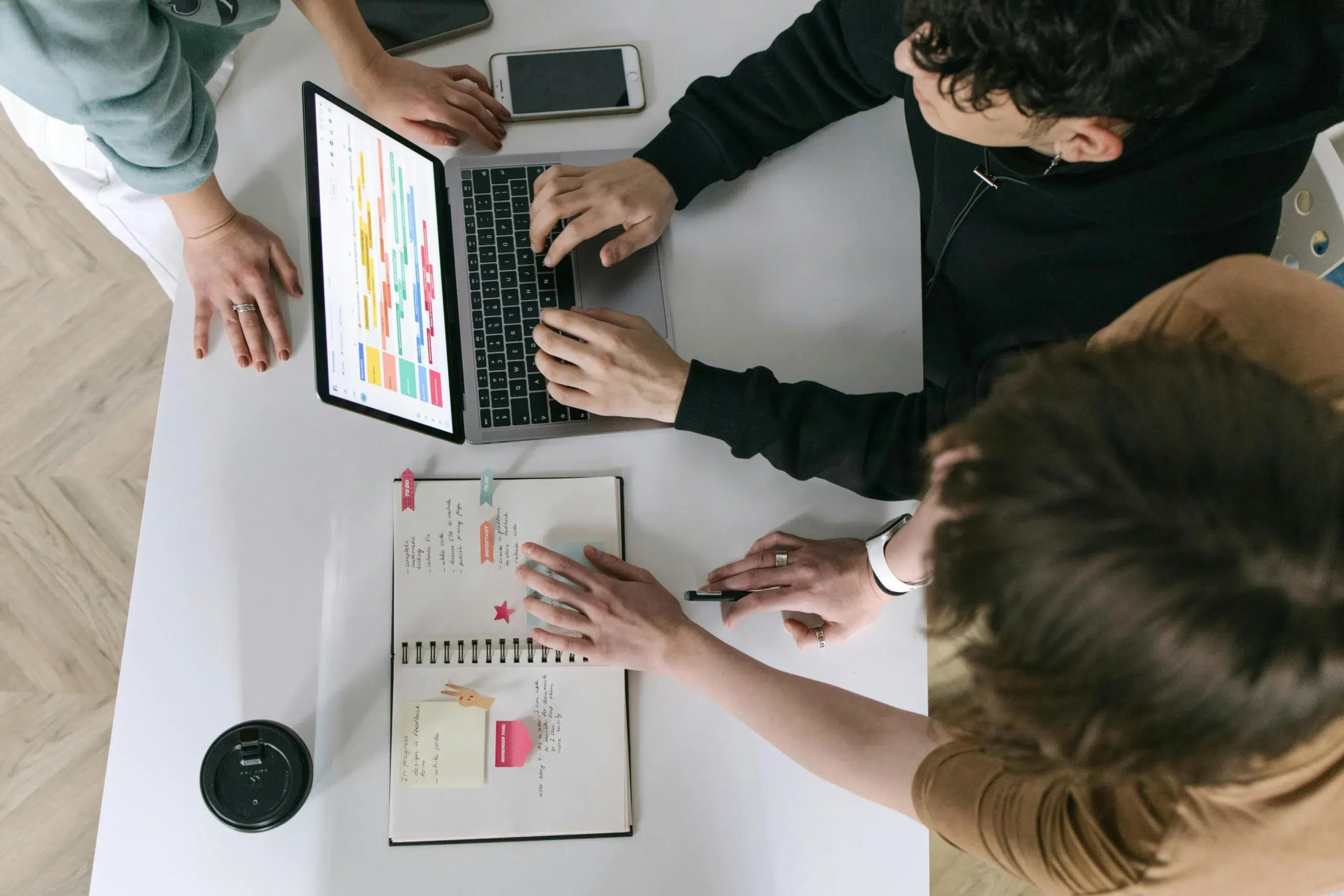 An overhead view of a team using a laptop to manage complex preventive maintenance scheduling and asset data on a digital dashboard.